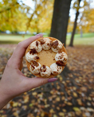 
                  
                    Load image into Gallery viewer, Hand holding a pumpkin tart autumn leaves and trees in the background
                  
                
