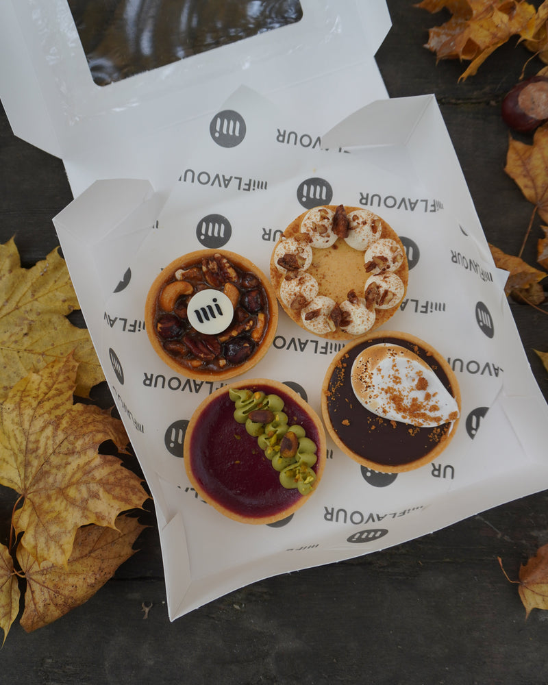 Packaging with dessert illustrations and text on a dark surface with autumn leaves.